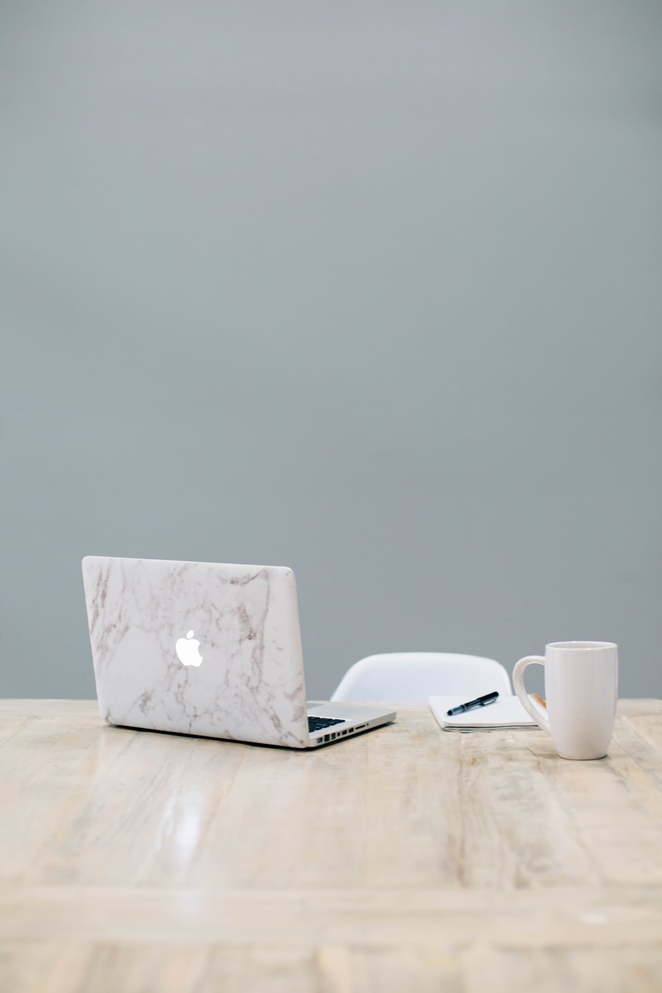 Laptop, notebook, and coffee mug on a wooden desk.