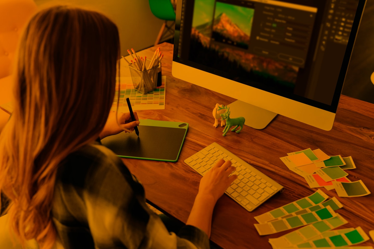 Graphic designer edits image on computer with tablet and keyboard.